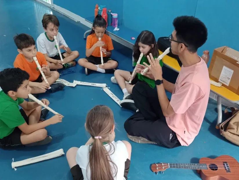 Professor tocando instrumento musical com alunos na Green Kids School